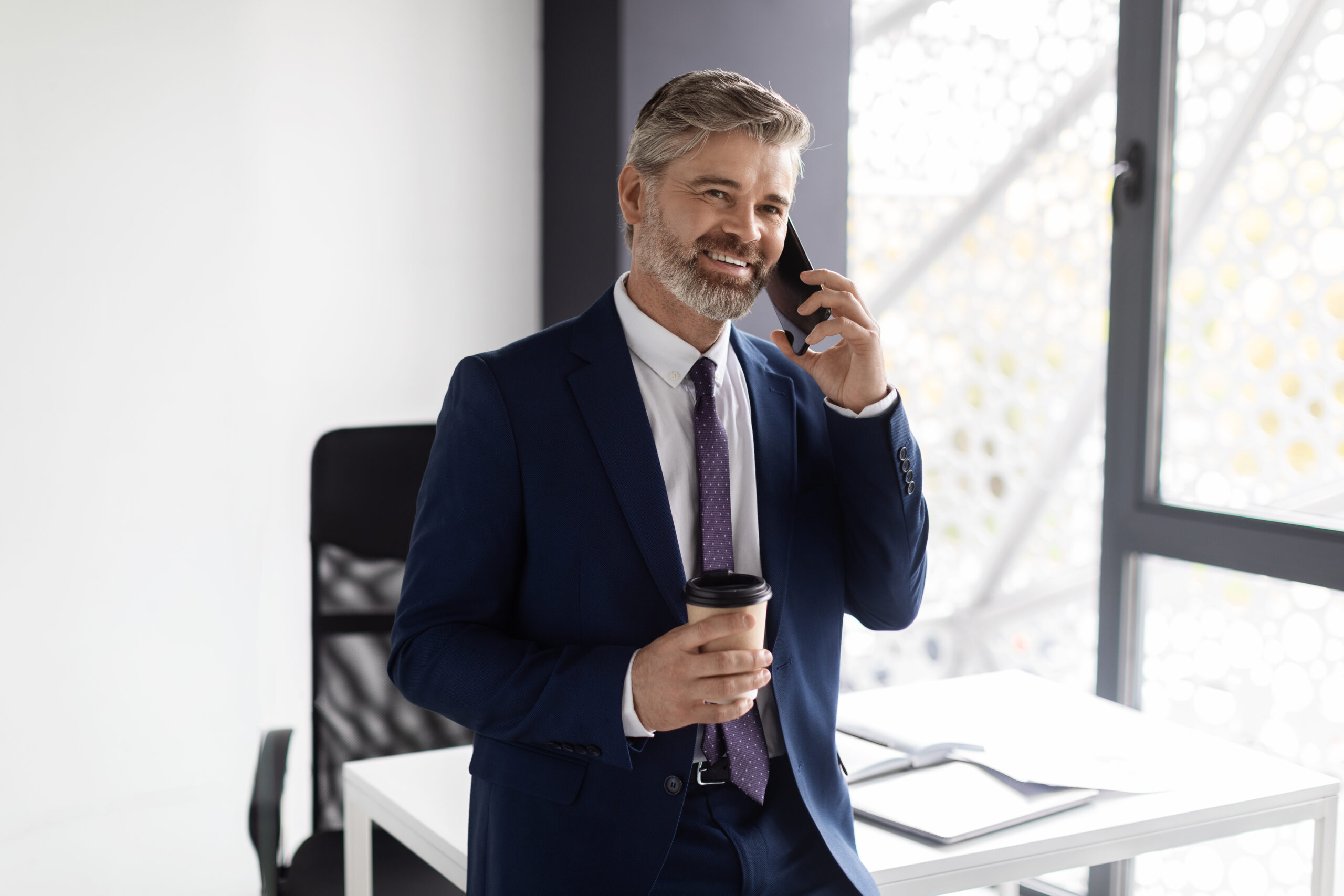 Handsome Middle Aged Man Talking On Cellphone And Drinking Coffee In Office