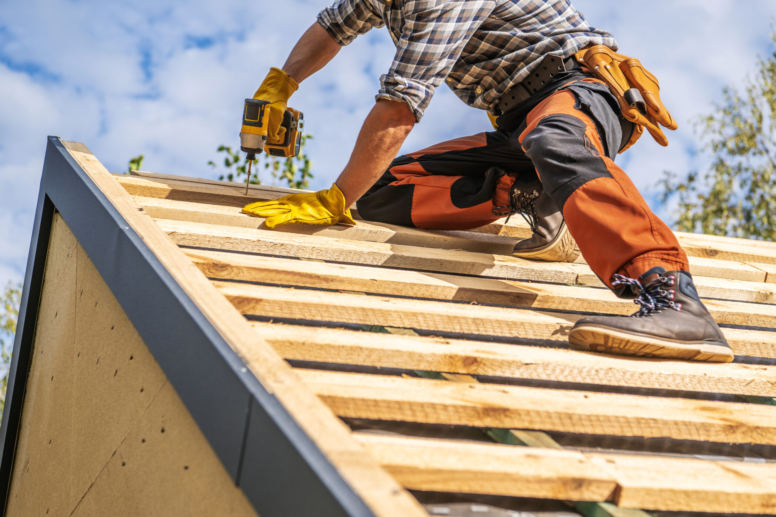 Roofing Contractor Attaching Wooden Elements to the House Roof Roofing Contractor Attaching Wooden Elements to the House Roof